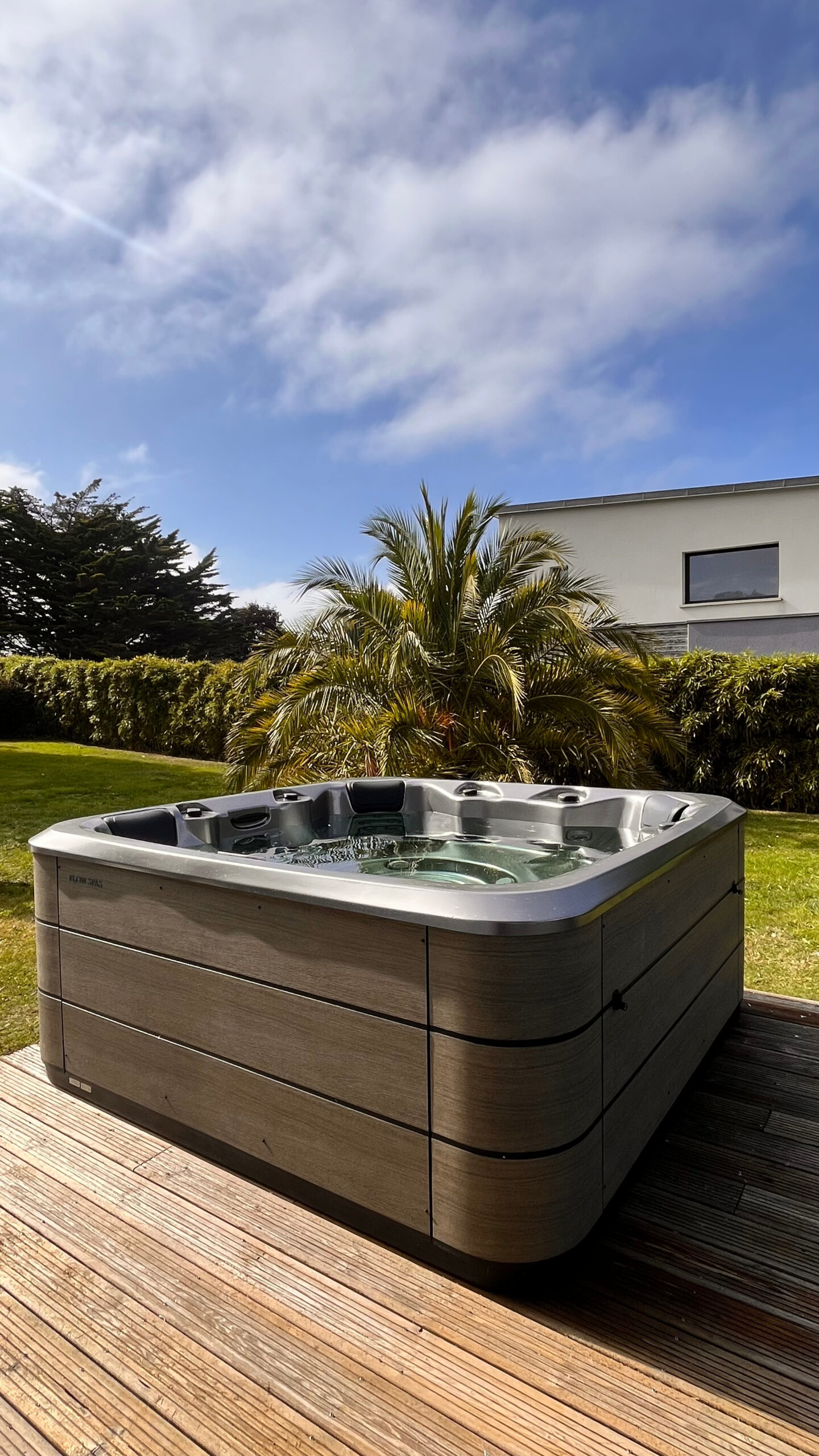 Spa gris moderne sur terrasse en bois dans un jardin à Plurien