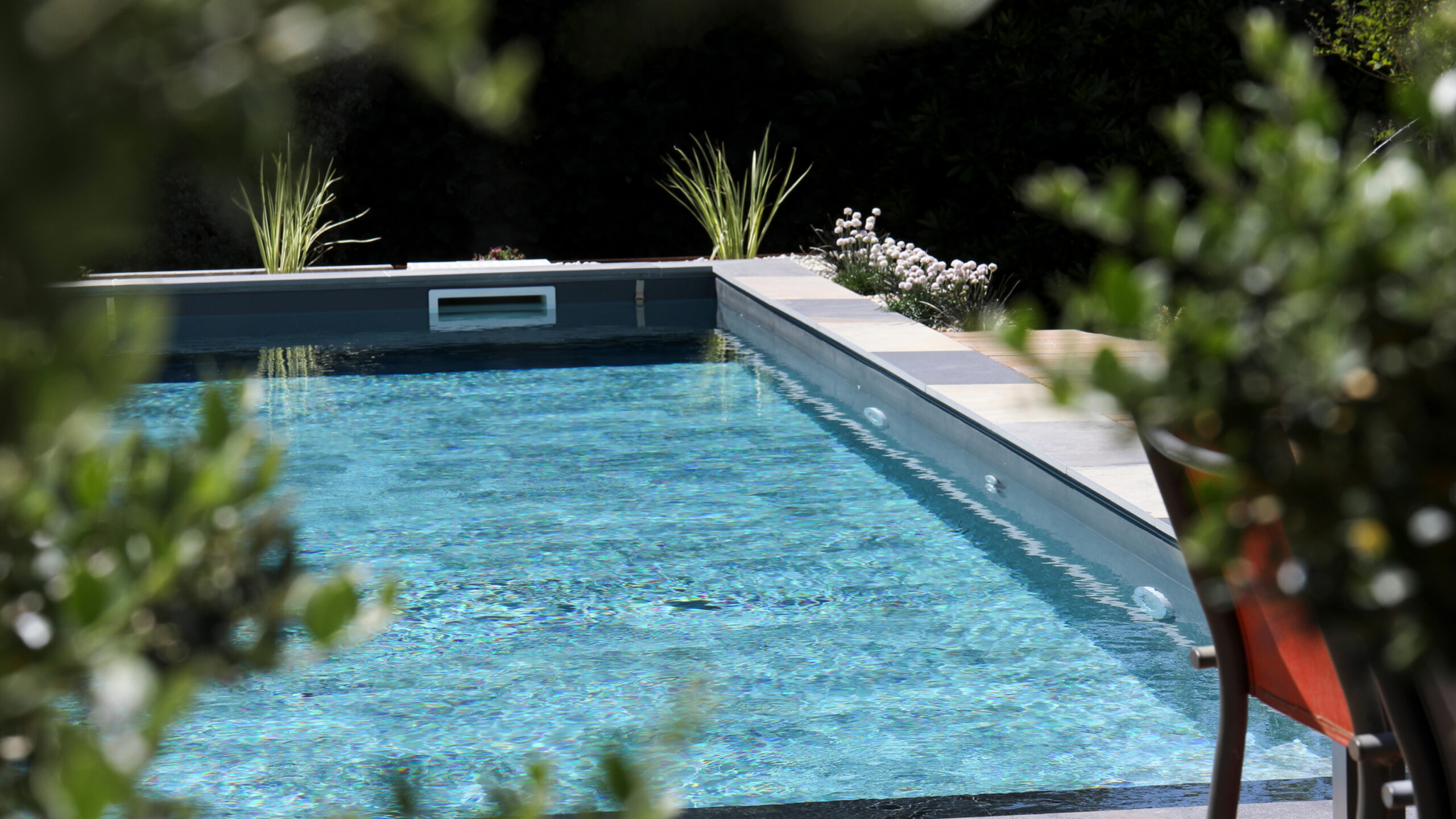 Piscine rectangulaire moderne à eau bleue dans un jardin verdoyant