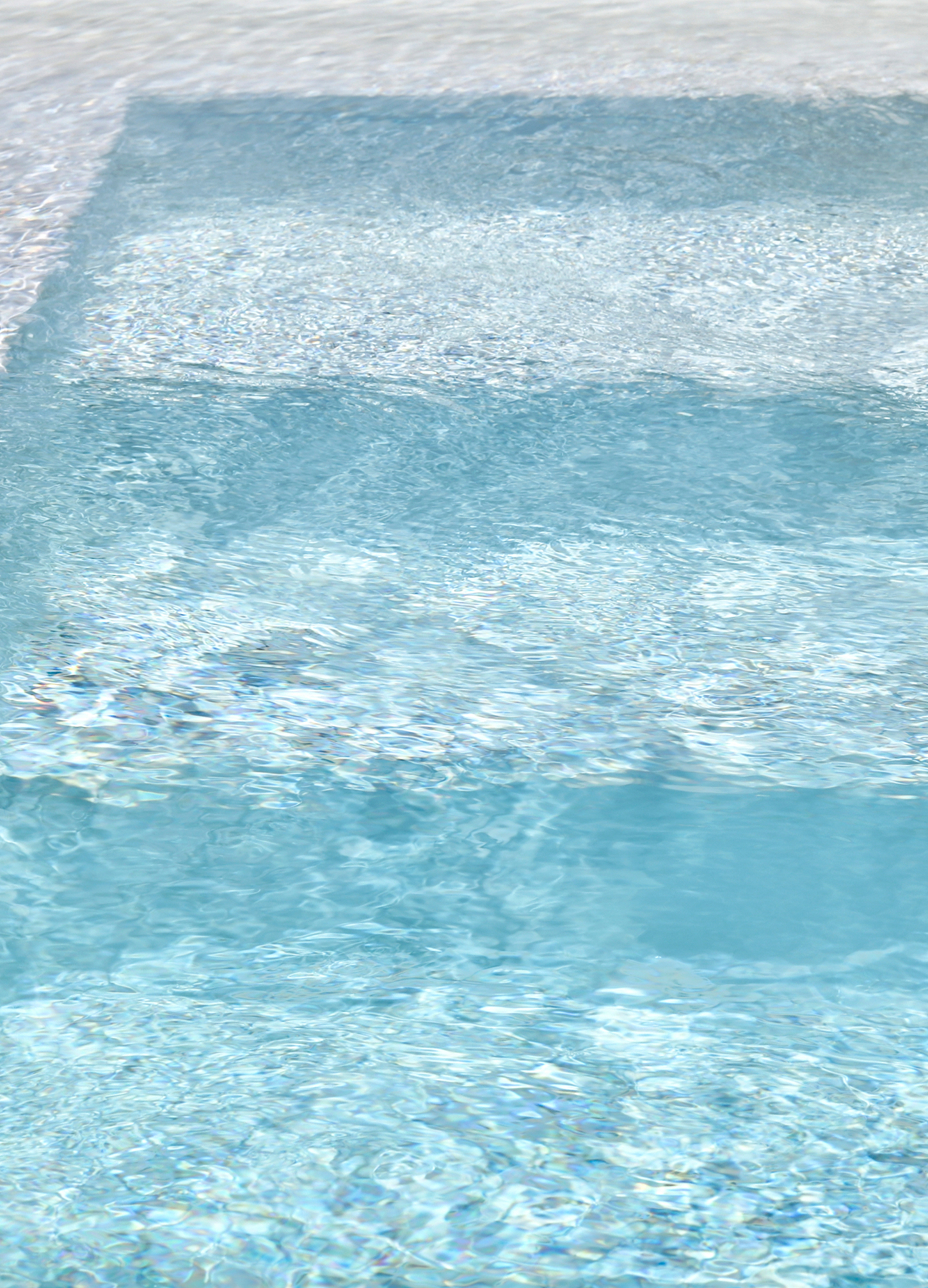 Vue plongeante sur des marches immergées dans une eau de piscine bleue