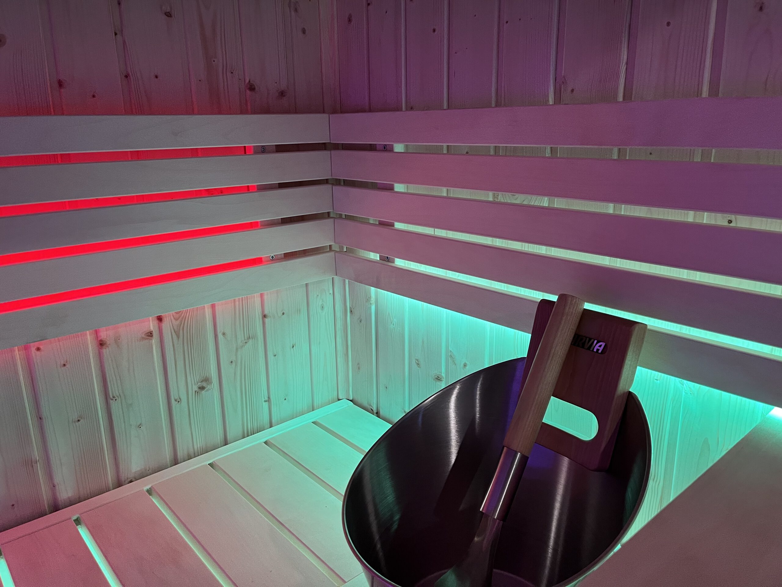 Intérieur de sauna infrarouge en bois avec éclairage LED rouge et turquoise